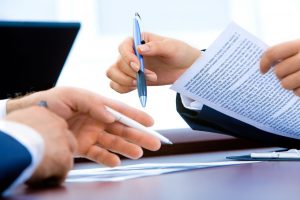 making an insurance claim is illustrated by two people's hands signing a document