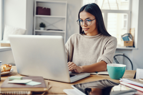 young woman sitting inside at laptop working for online business