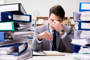 young businessman under stress due to peak season work surrounded by files