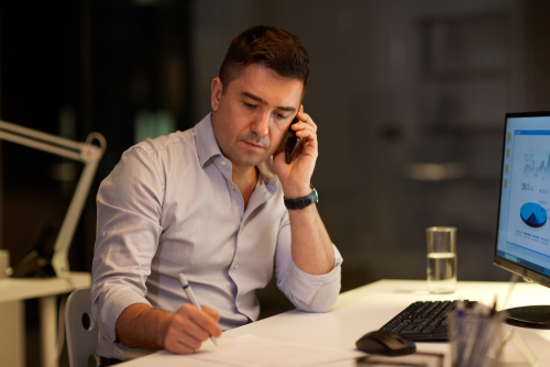 man on phone to customer offering good customer service while at his desk running a business