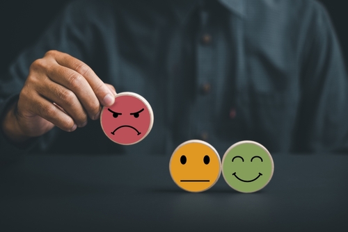 Unsatisfied customer holding frown icon on wooden circle.