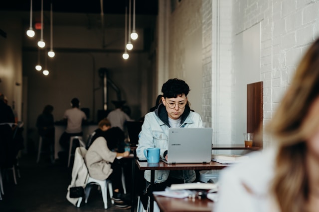 A women pest inspector sits at a coffee shop while upskilling on her laptop with a Rapid Solutions short online course in timber pest control