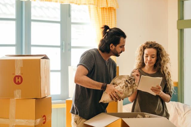 A couple move into a new home and look at their pest control quote while weighing up all their moving costs